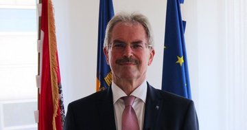 Landtagspräsident Karl Wilfing vor den Fahnen von Österreich, Niederösterreich und Europa