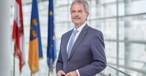 Präsident Karl Wilfing im NÖ Landtag; im Hintergrund die Fahnen Österreichs, Niederösterreichs und der EU