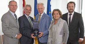 Gruppenbild bei der Geschenksübergabe vor Fahnen