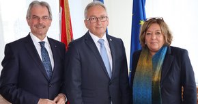 Zwei Männer und eine Frau vor Fahnen