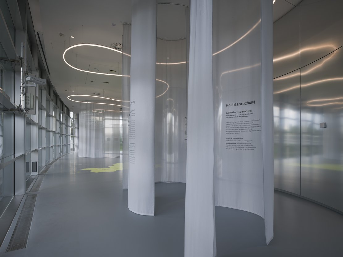 Innenansicht des Forum Landtag. Weiße geschwungene Wände mit Erklärungstexten.